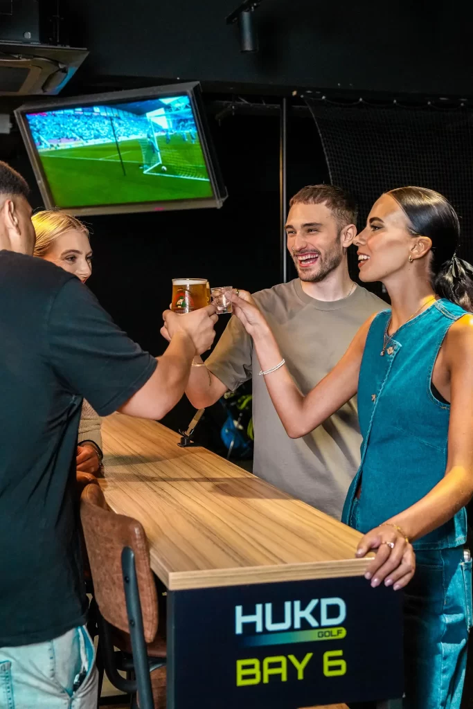 A group of friends toasting with their drinks at Hukd Golf