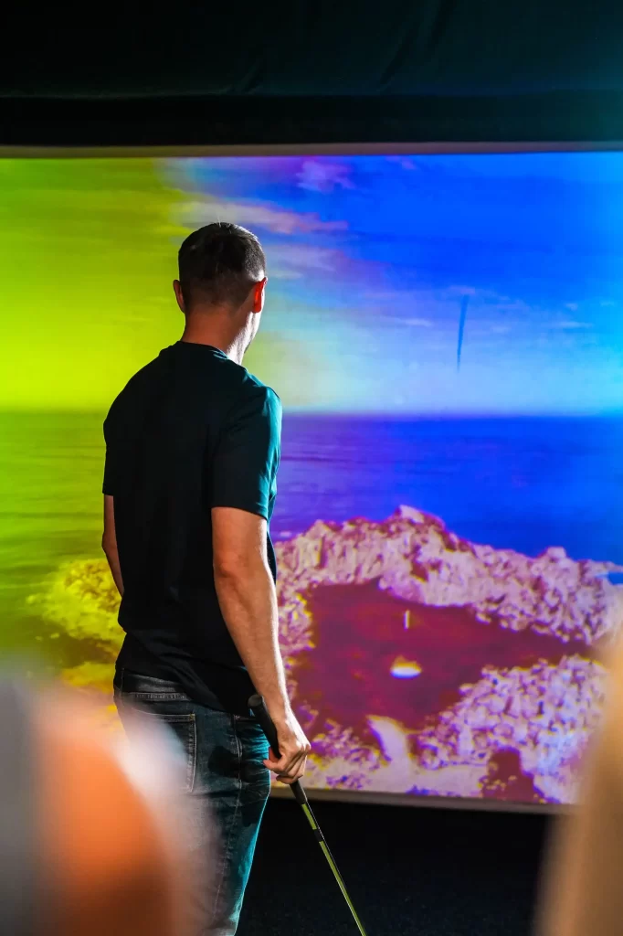 A man playing a links golf course on the trackman simulator