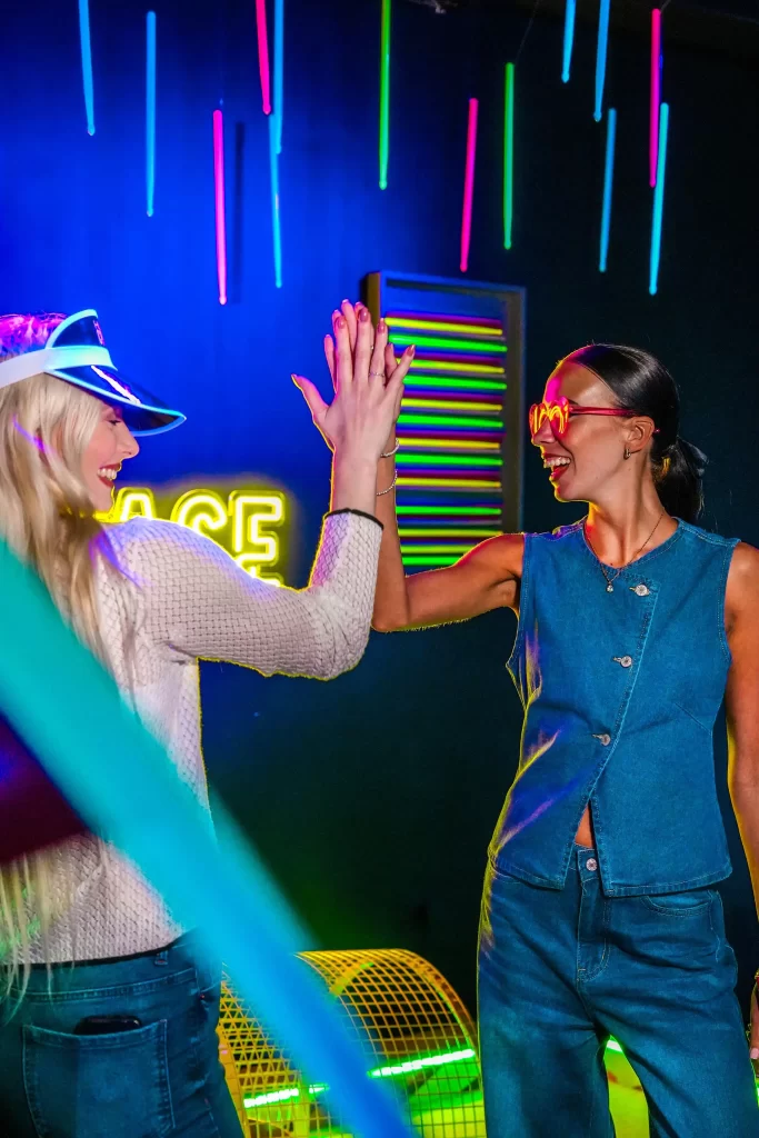Two women hi-fiving while playing crazy golf at Hukd